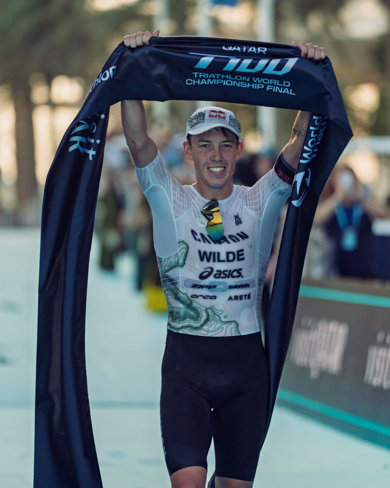 Triathlete crossing the finish line wearing an OMIUS cooling cap